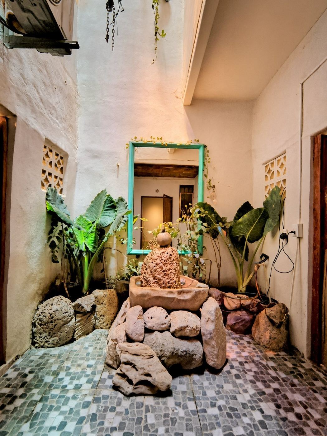 The courtyard at La Casa Grande, a stone fountain among elephant ears and mosaic tile