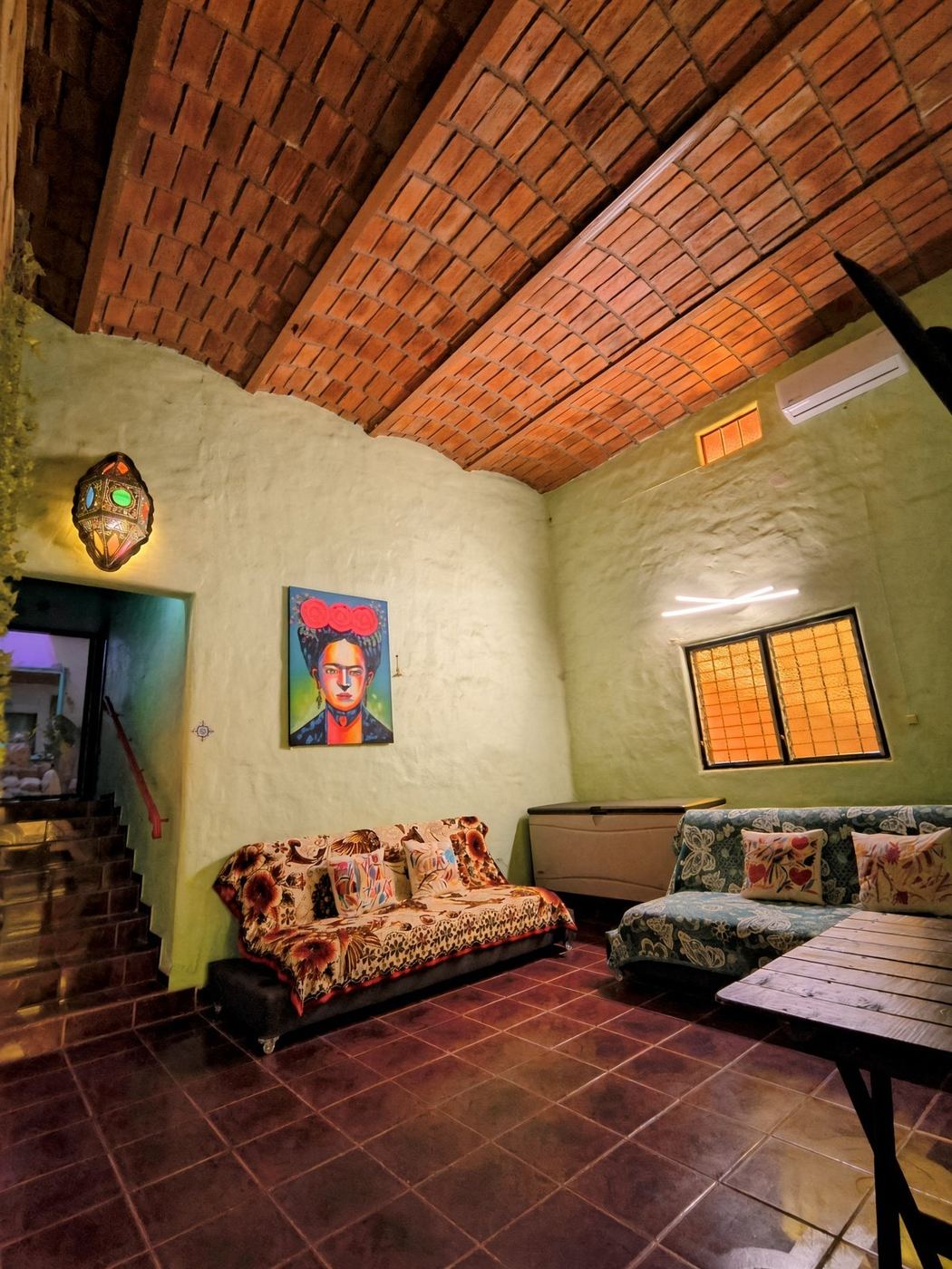 Evening in the salon at La Casa Grande, brick ceiling, a painted portrait, and sofas under a lantern