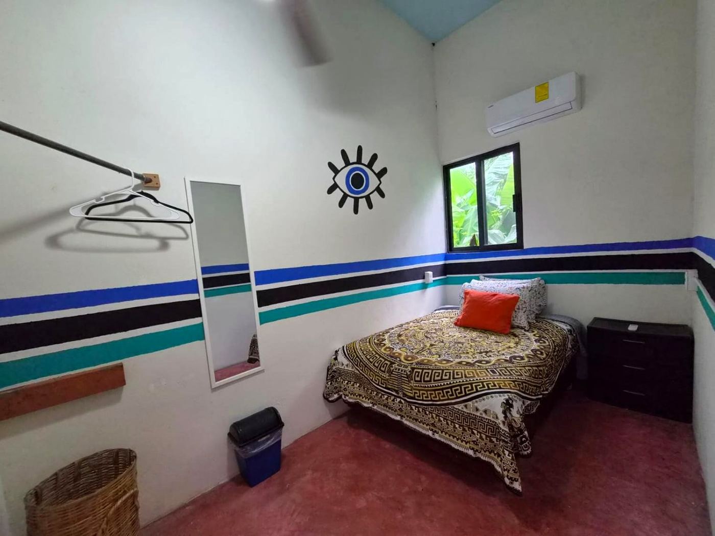 The same bedroom at Two bedroom Delight, mirror, striped walls, and the garden in the window