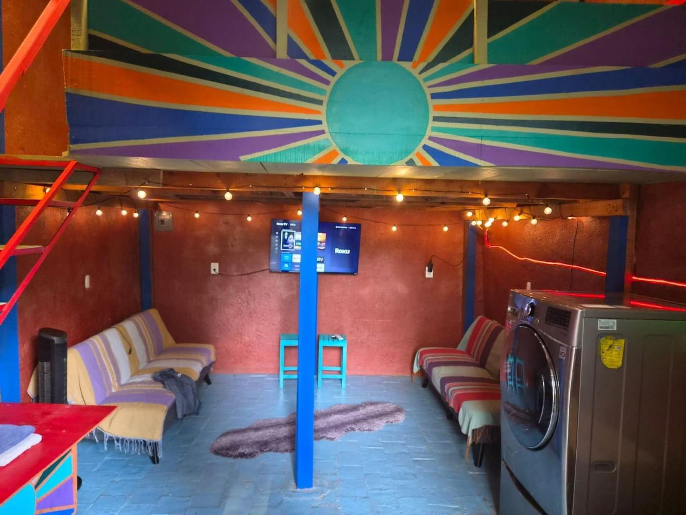 Two bedroom Delight, a painted sun under the loft, string lights, and daybeds on a blue floor