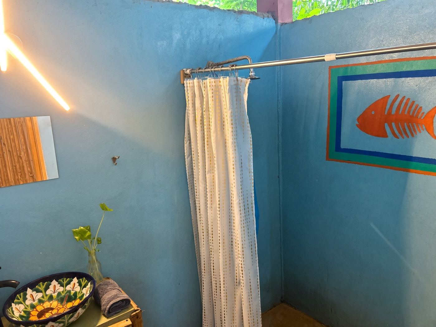 The bath at El Loft, a blue wall, an orange fish, and a sunflower sink