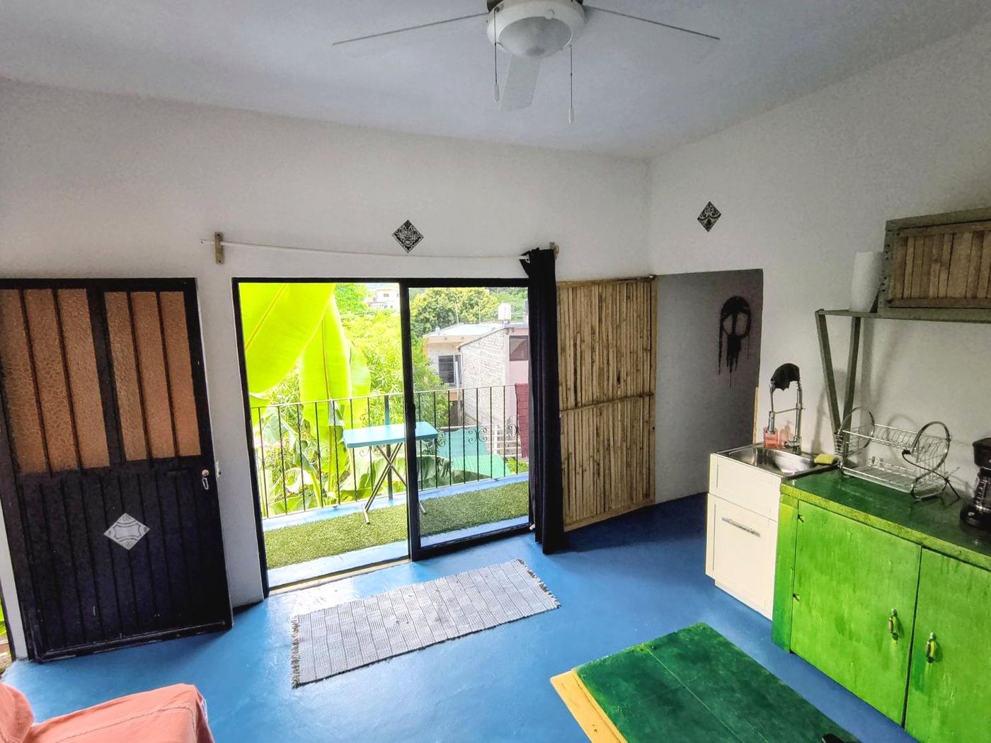 Casita Sol, blue floor and a green kitchen, the balcony open to banana leaves