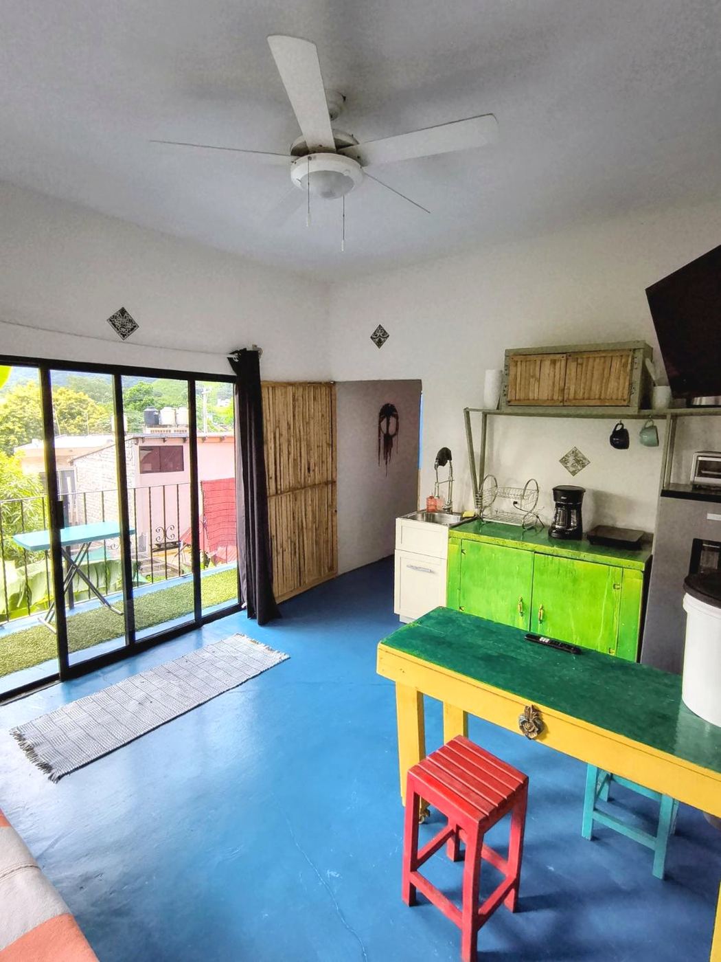 The living room at Casita Sol, a yellow table, green cabinets, and the balcony doors